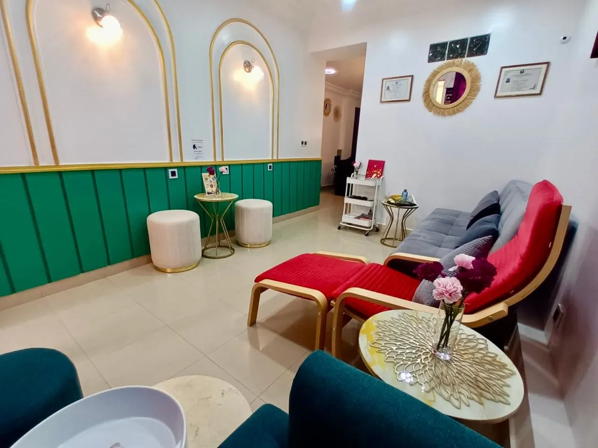 Le salon en entier : panneaux bleu canard, arches dorées, fauteuils rouges et vasque de pédicure