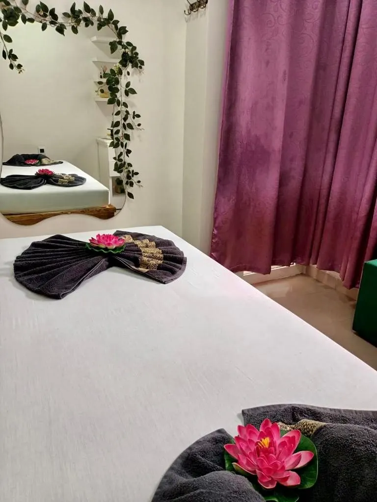 Salle de soin : serviette noire pliée en éventail, lotus rose, lierre et rideau mauve