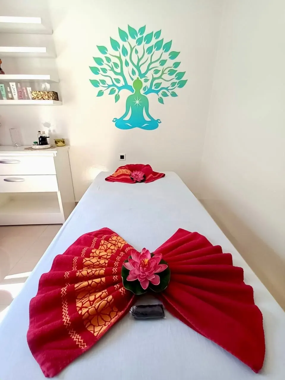 Serviette rouge à motifs thaïs pliée en éventail avec un lotus rose