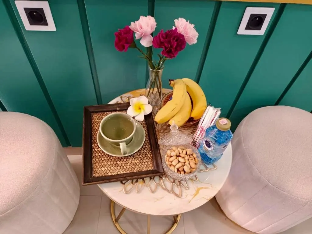 Le plateau du thé sur une table dorée entre deux poufs blancs : thé, bananes, cacahuètes et œillets